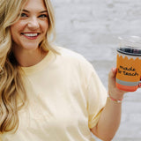 Woman holding a cup with text against a light background