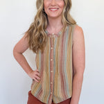 Woman wearing a striped sleeveless top and brown shorts against a white wall