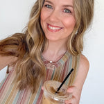 Woman holding a iced coffee drink with a straw against a white background