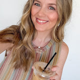 Woman holding a iced coffee drink with a straw against a white background