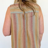 Person wearing a sleeveless striped shirt and red shorts against a white wall.