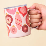 Hand holding a mug with decorative patterns on a beige background