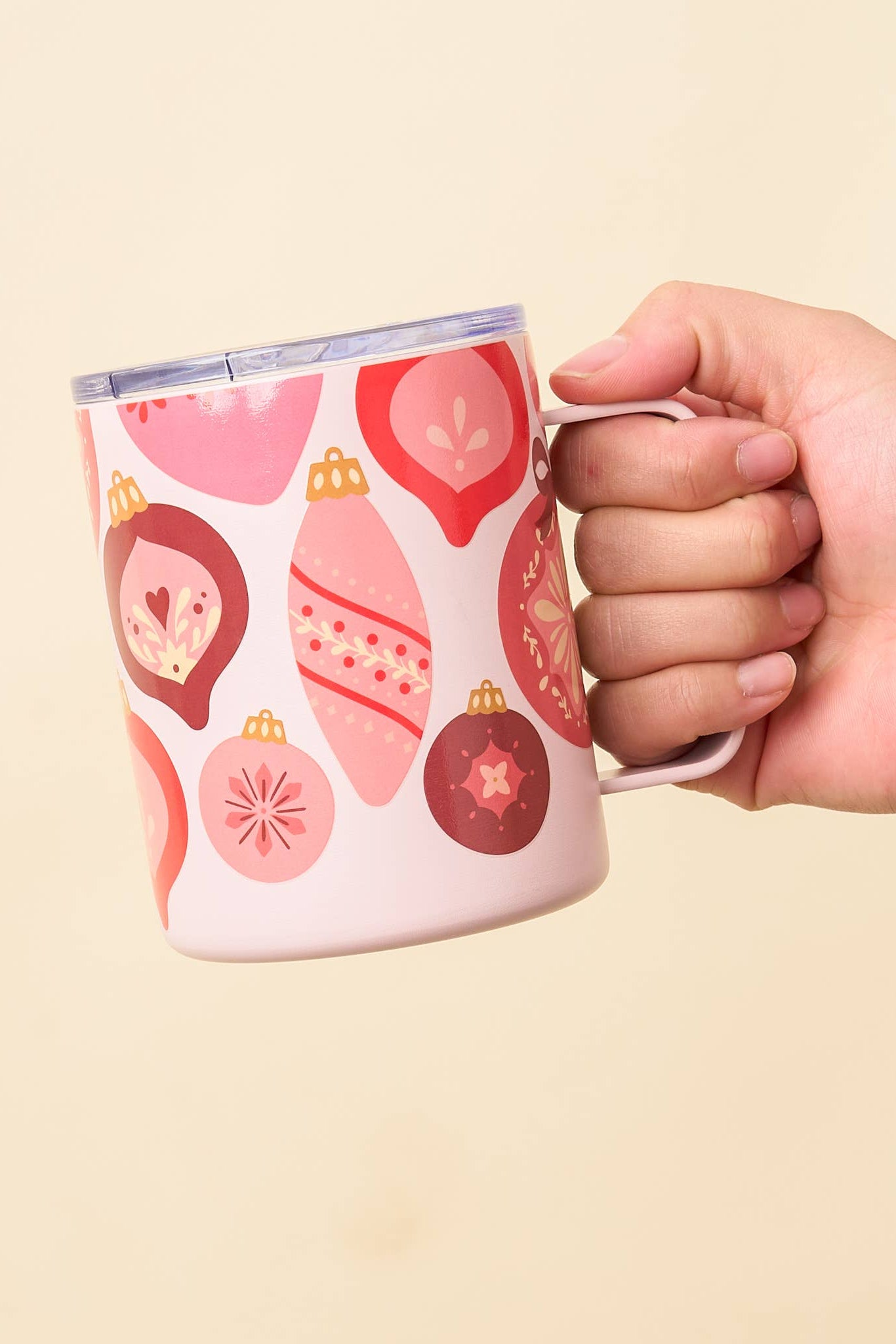 Hand holding a mug with decorative patterns on a beige background