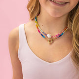 Young girl wearing a colorful beaded necklace against a pink background