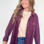 Woman wearing a purple jacket over a white shirt and blue jeans on a white background