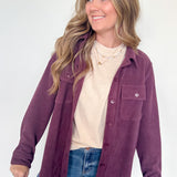 Woman wearing a purple jacket over a white shirt and blue jeans on a white background