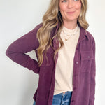 Woman wearing a purple jacket over a white shirt and blue jeans on a white background
