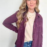 Woman wearing a purple jacket over a white shirt and blue jeans on a white background