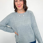 Woman wearing a light blue sweater and blue jeans against a white background