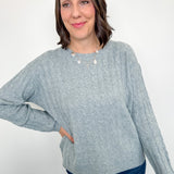 Woman wearing a light blue sweater and blue jeans against a white background