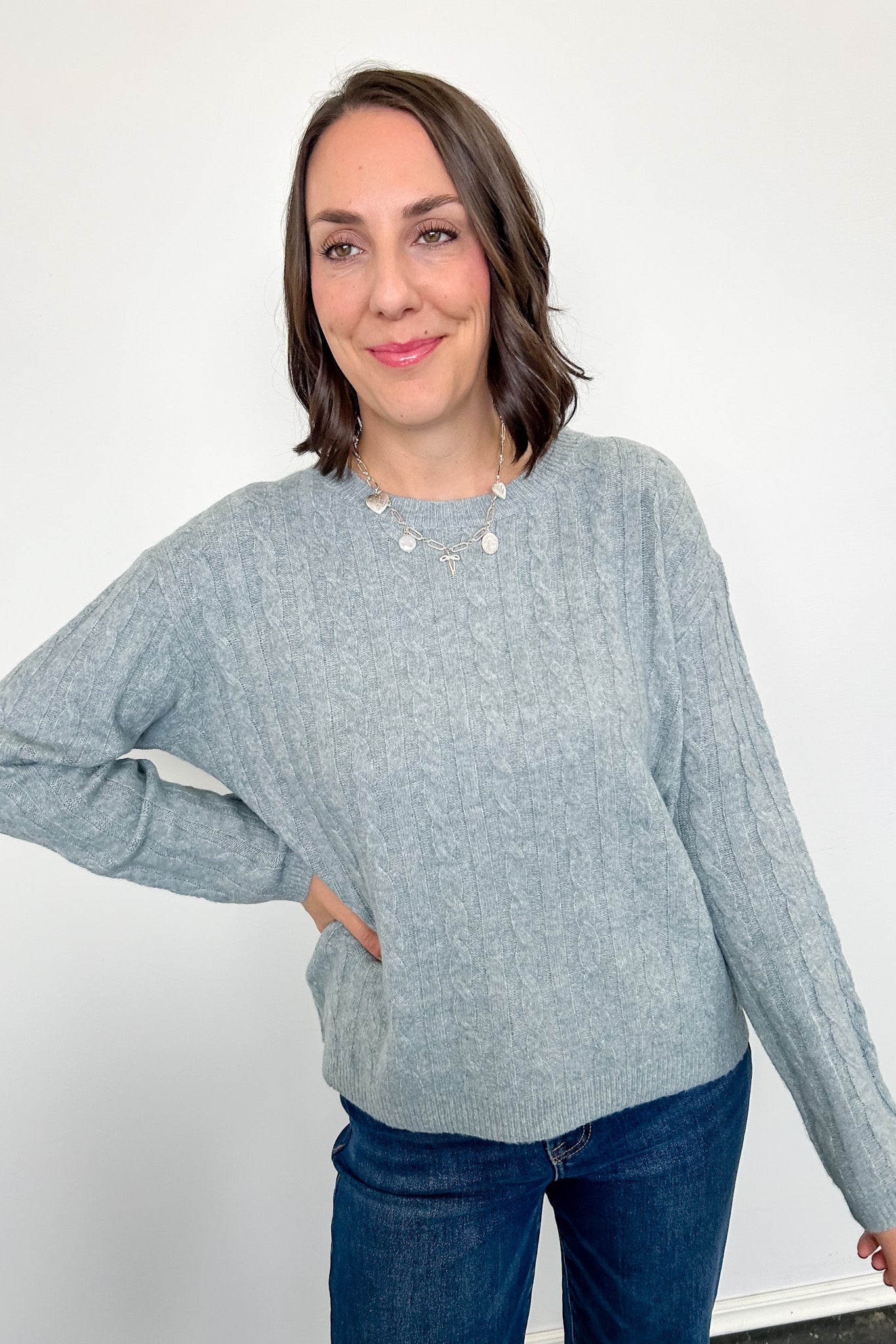 Woman wearing a light blue sweater and blue jeans against a white background