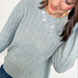 Woman wearing a light blue sweater with a plain background