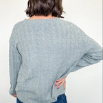 Person wearing a light blue sweater and blue jeans against a white background