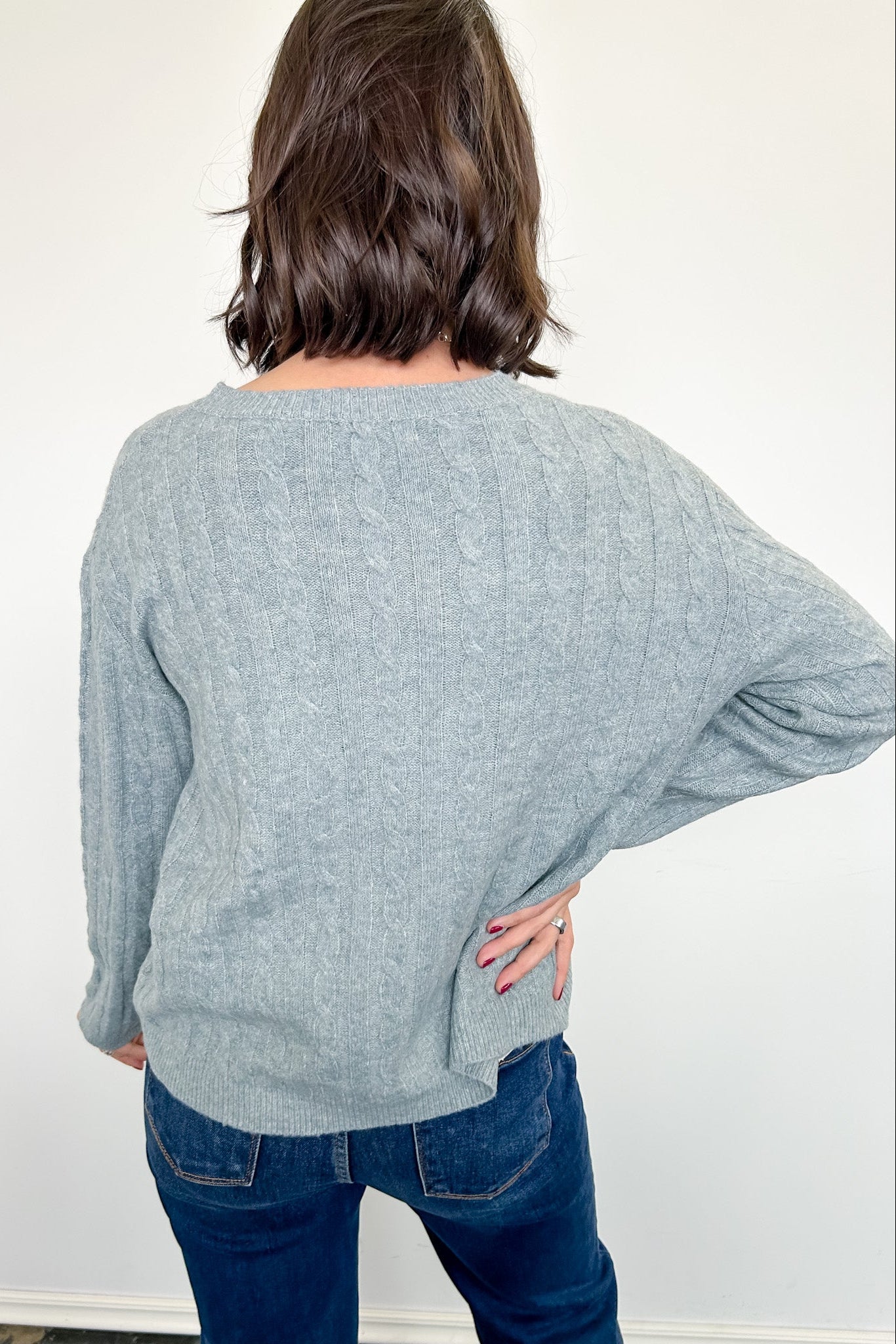 Person wearing a light blue sweater and blue jeans against a white background