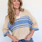 Woman wearing a beige and blue striped sweater against a white background