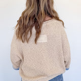 Person wearing a beige sweater with a pocket on a white background