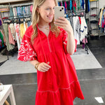 Poppy colored dress. Collared. Tiered detailing. Hits above the knee. Pattern on the short sleeves in white.