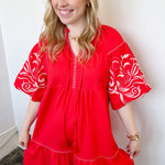 Poppy colored dress. Collared. Tiered detailing. Hits above the knee. Pattern on the short sleeves in white.