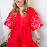 Poppy colored dress. Collared. Tiered detailing. Hits above the knee. Pattern on the short sleeves in white.