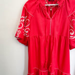 Poppy colored dress. Collared. Tiered detailing. Hits above the knee. Pattern on the short sleeves in white.