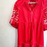 Poppy colored dress. Collared. Tiered detailing. Hits above the knee. Pattern on the short sleeves in white.