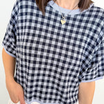 Person wearing a black and white checkered top with a plain background
