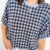 Person wearing a black and white checkered top with a plain background