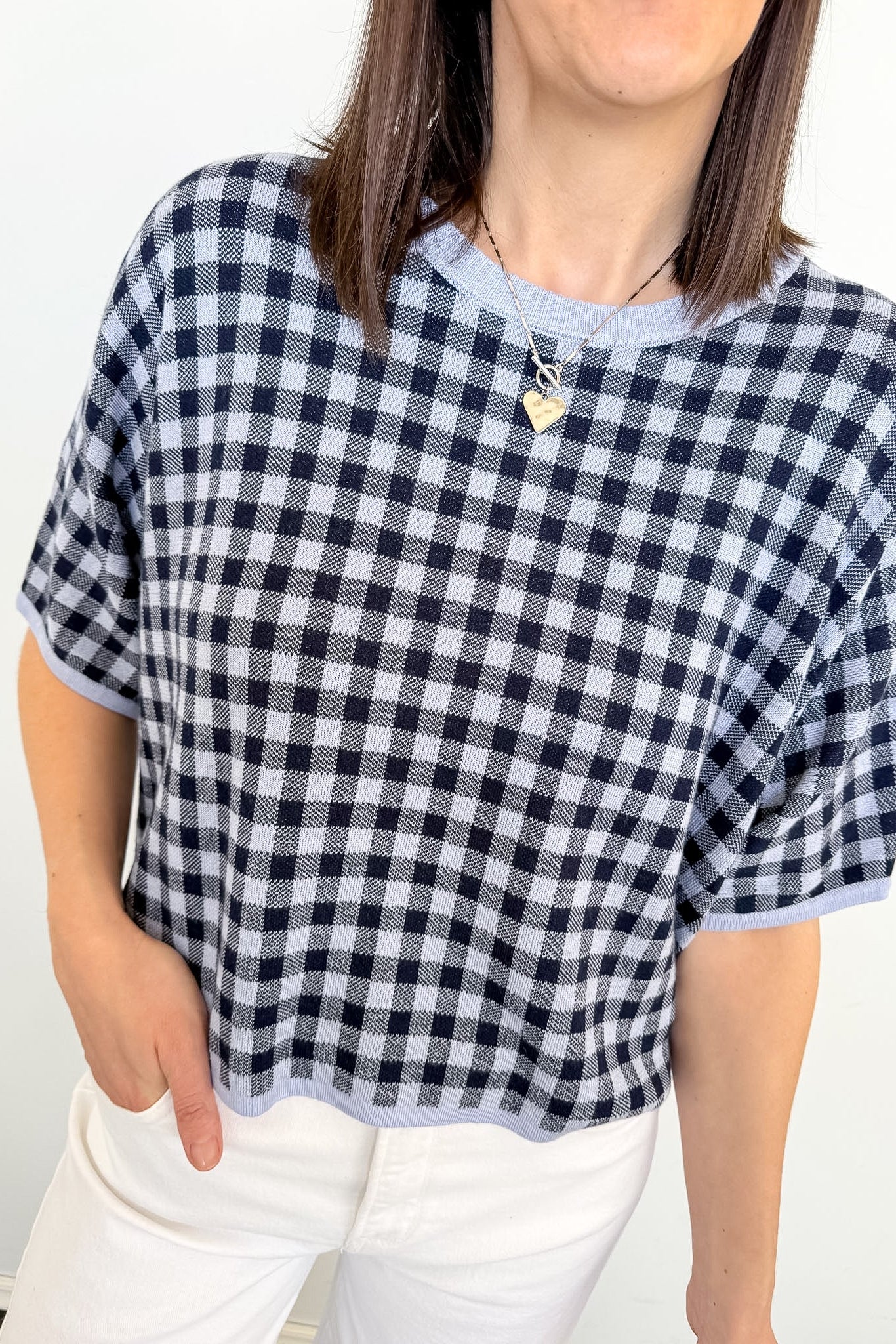 Person wearing a black and white checkered top with a plain background