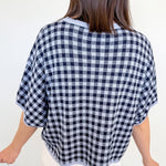 Person wearing a black and white checkered poncho against a plain background