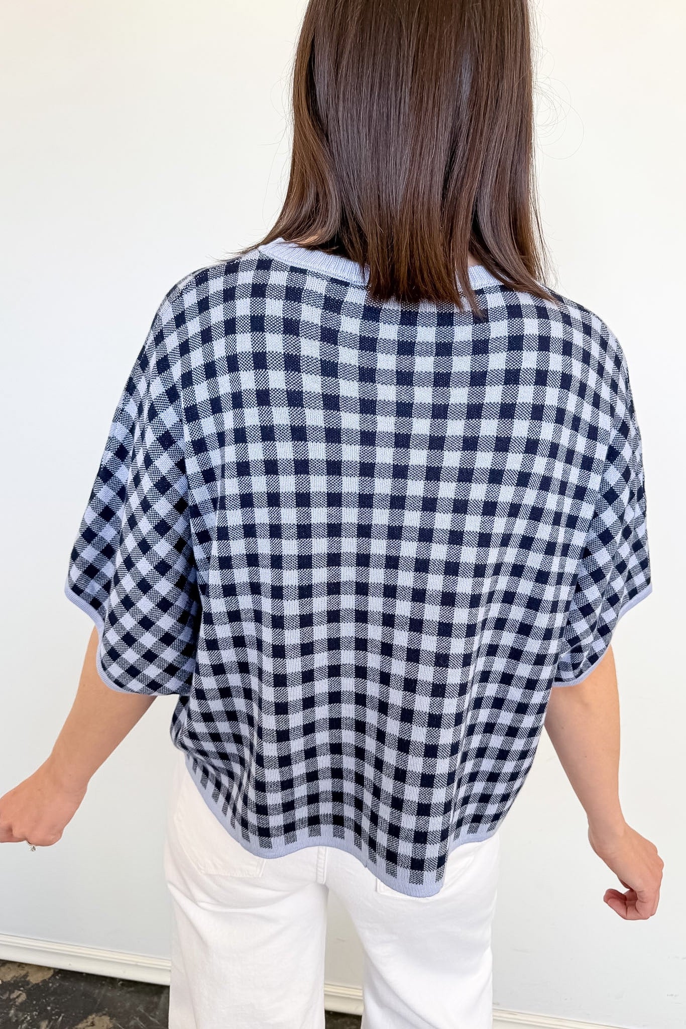 Person wearing a black and white checkered poncho against a plain background