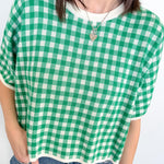 Person wearing a green and white checkered shirt with a plain background