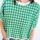 Person wearing a green and white checkered shirt with a plain background