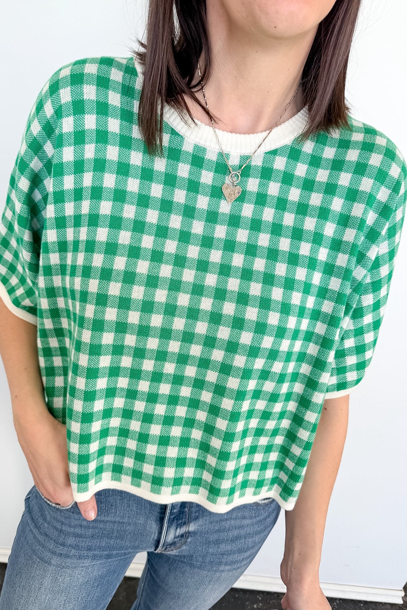 Person wearing a green and white checkered shirt with a plain background