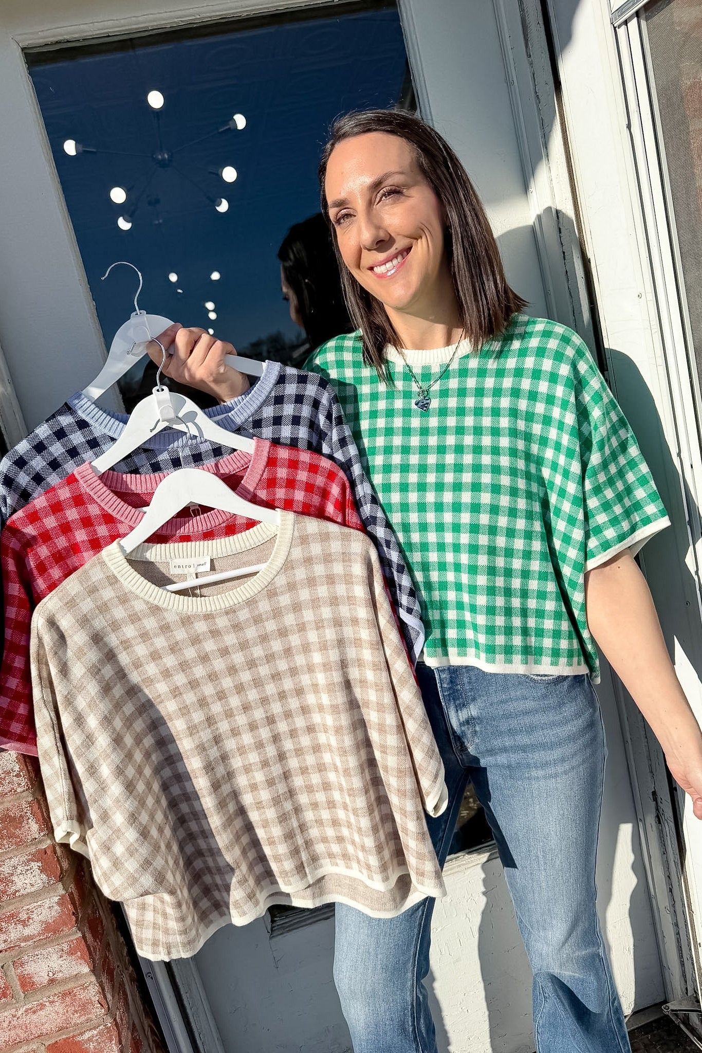 Woman holding a rack of checkered shirts outdoors