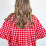 Person wearing a red and white checkered shirt against a plain background