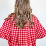 Person wearing a red and white checkered shirt against a plain background