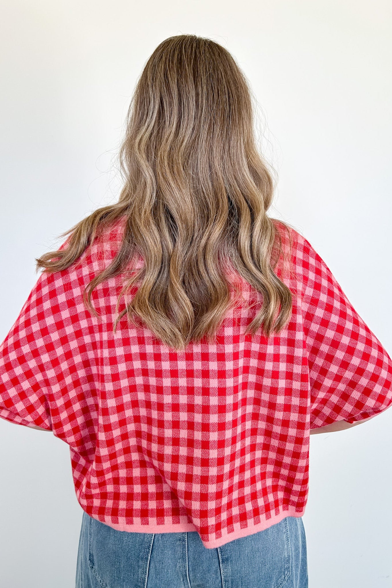 Person wearing a red and white checkered shirt against a plain background