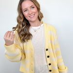 Woman wearing a yellow and white striped cardigan over a white shirt with a plain background