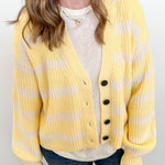 Person wearing a yellow and white striped cardigan over a white shirt and blue jeans against a white background
