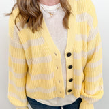 Person wearing a yellow and white striped cardigan over a white shirt and blue jeans against a white background