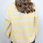 Person wearing a yellow and white striped sweater against a plain background