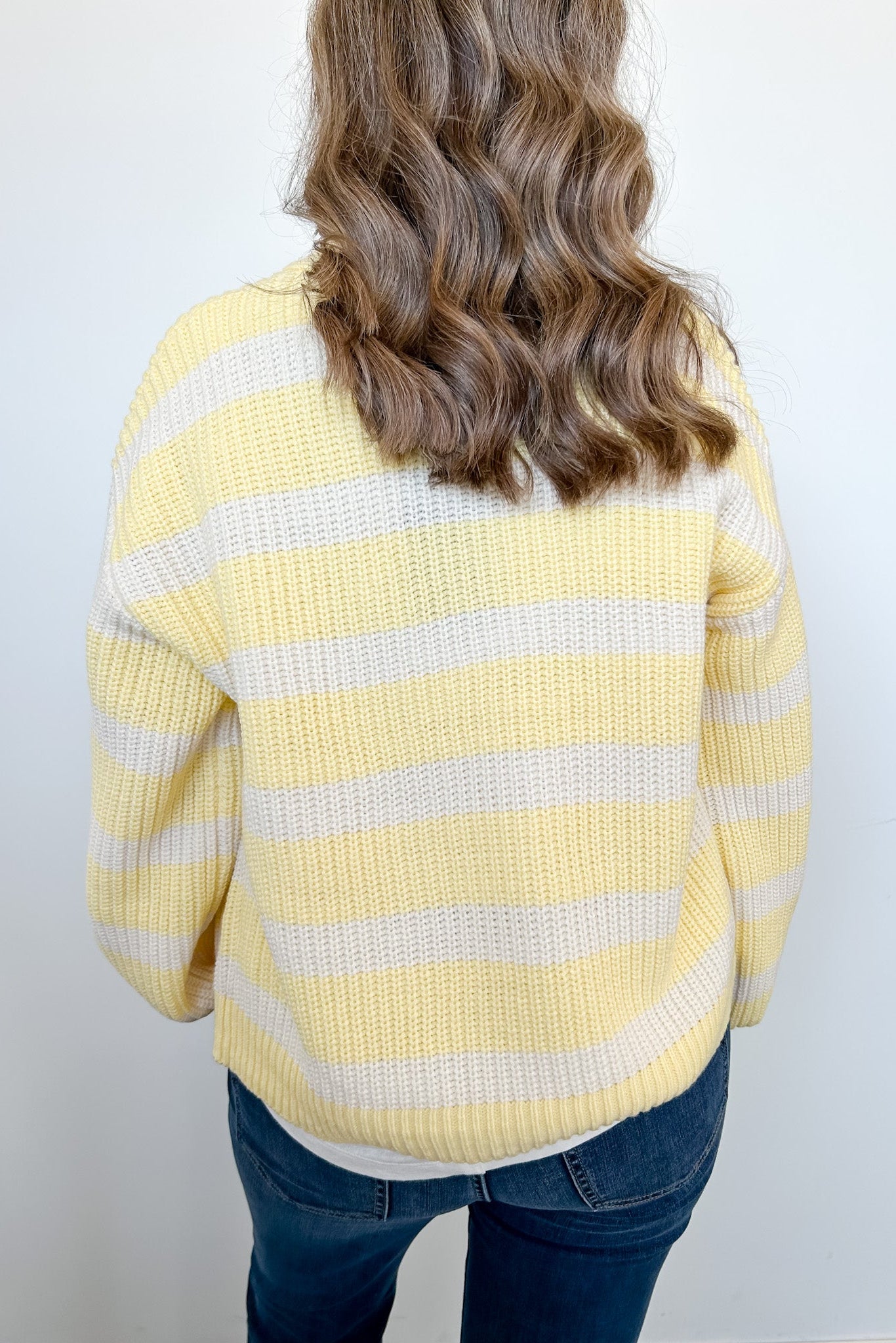 Person wearing a yellow and white striped sweater against a plain background