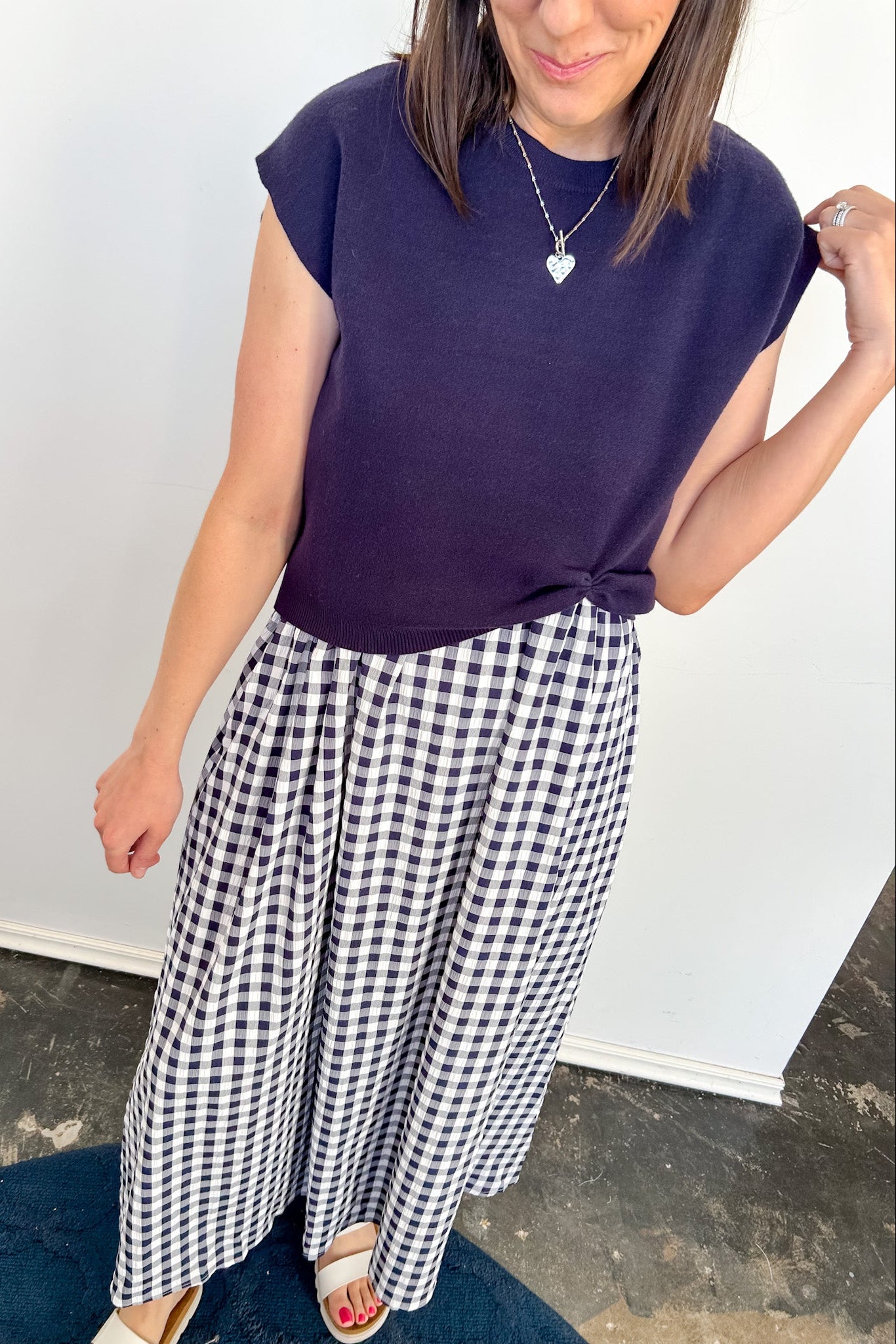 Woman wearing a purple top and black and white checkered pants against a plain background
