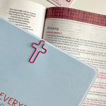 Open book with pink cross bookmarks on a white surface