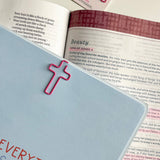 Open book with pink cross bookmarks on a white surface