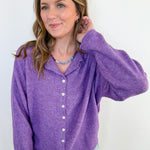 Woman wearing a purple button-up shirt against a white background