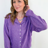 Woman wearing a purple button-up shirt against a white background