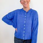 Woman wearing a blue cardigan against a white background