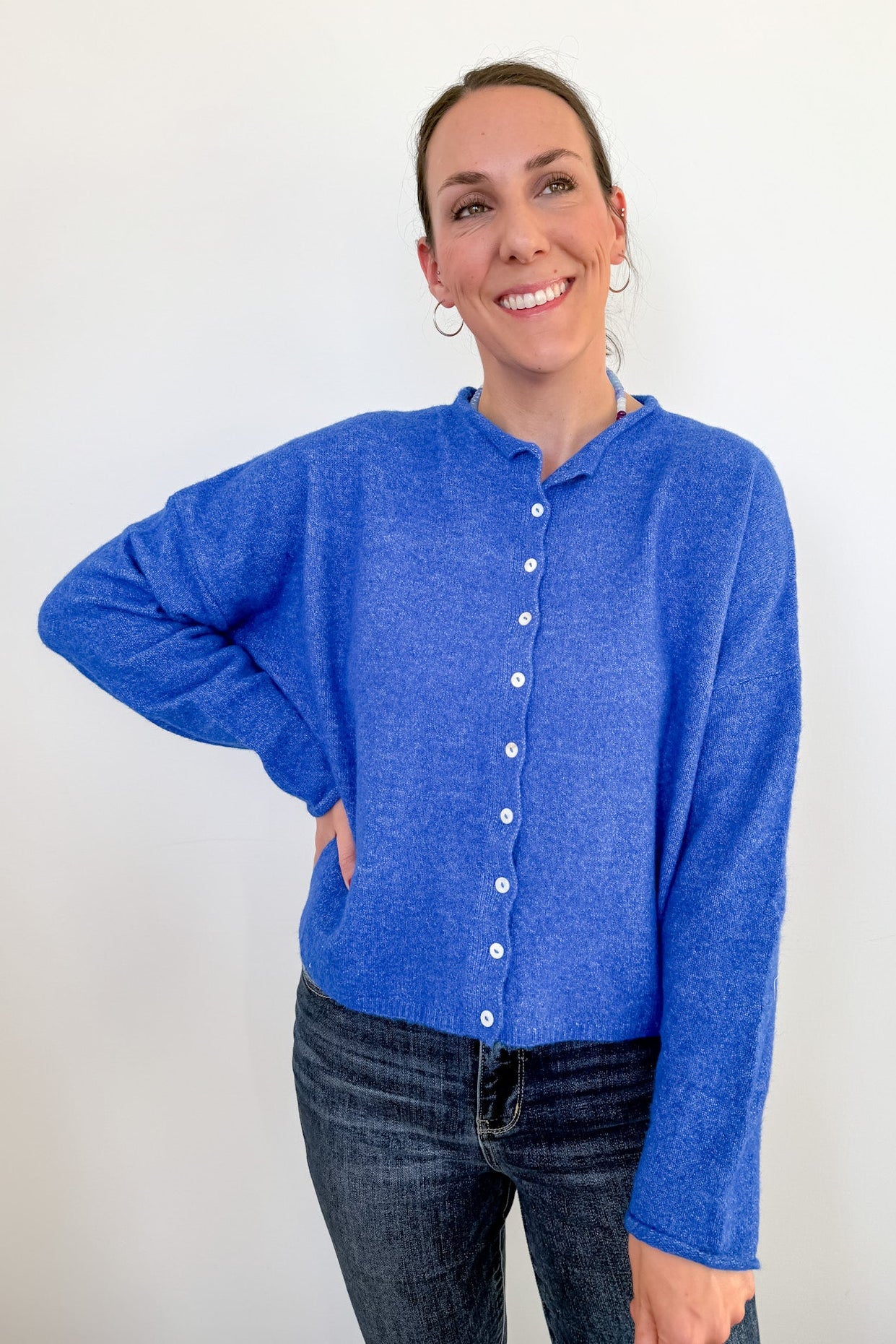 Woman wearing a blue cardigan against a white background