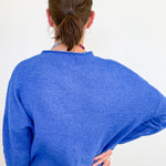 Person wearing a blue sweater from behind on a white background